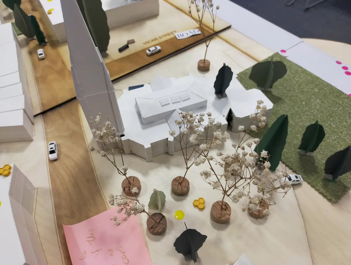 Looking to be the centrepiece of our exhibition, we proposed to create a site model of Dudley Highstreet at 1:200 scale with buildings modelled in a simple form. Local residents and visitors to the exhibition are then invited to decorate a chosen building to how they would envision it sat within the context of a greener Highstreet. We want to tie in our themes of biodiversity and materials by proposing that buildings can, and do, have the potential to be a lot healthier, sustainable, and interactive on the street. This site model also helps gain vital public opinions on the Highstreet and prompts discussion of areas most in need of attention.

To ensure that the model is utilising the MDF to the most efficient standard possible. First, the centres of the massing blocks have been hollowed out. This allows a reduction in materials used as other buildings can be cut in the centres of the model. Then the top is finished with a solid piece.
The waste material is placed into the recycling rack where other students can reuse it; otherwise, if the material left cannot be used for another project, it is recycled correctly by the university.

The model spanned just over 3.4m long and over 50cm wide. With the majority being cut from scrap woods that would fit the jigsaw of the shape, we were able to drastically cut down on waste. We also got some small benches and bee hives printed from recycled plastics, and used dried flowers as trees to represent the green spaces. Ultimately, the model seemed like a huge success, and really helped portray our ideas about Dudley High Street to those who came by. Everyone from Dudley who saw the model knew that it was the High Street, and interacted well with it. The size did make it difficult to move, especially to carry to the site, but it sat nicely in the centre of the the room and really drew people in to interact with it.

The model brought people in from outside to play with, write on, interact with. It became a spectacle for the public to come in and see what was happening and offer their ideas about what could be done.

The event was a success. Many people from the public (those who heard about the event, and those who just happened across it on the day) came in to interact with the model, which sat as the centre piece in the room. Kids liked to play with the pieces while the adults talked about things that could come from actions to help the High Street, not just leave it as is.

SOME OF THE KEY IDEAS WERE:
- The Shops need to be inviting for everyone. It’s no good having these places to go if people would rather take a bus to the next town.
- Just putting up boards across the windows is awful. Paint, Posters, Graffiti: Anything that actually makes the High Street look still alive is better than just wooden boards.
- More Green is needed. While it is obvious that there is a lack of Trees, many people wanted to push for these small bushes or planting spaces that could easily be implemented across the street.
- Spaces for public events or for people to at least gather at. While there is the Market and Fountain, it is not enough for the people of Dudley.
- Something needs to be done about the cars on the High Street. Some were Pro-Removal of all Cars, while some just wanted to limit when they could access the High Street.

Following the exhibition we created a series of drawings with our own interpretation of Sarah Wigglesworth ‘The Dining Table’ drawing. The drawings are a perfect representation of the our interactive model at the ERA Environmental Exhibition and Event. Showing the interaction the public had with the model, as well as the conversations that were held around the model. - Table 8.png